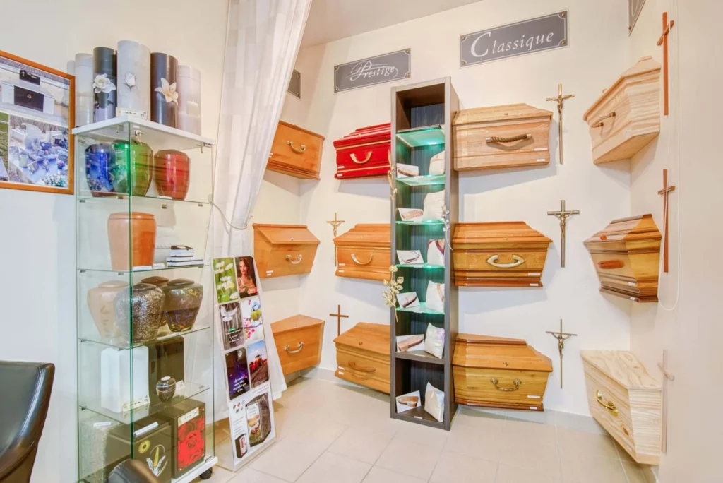 Exposition de cercueils en bois et urnes cinéraires en agence funéraire.