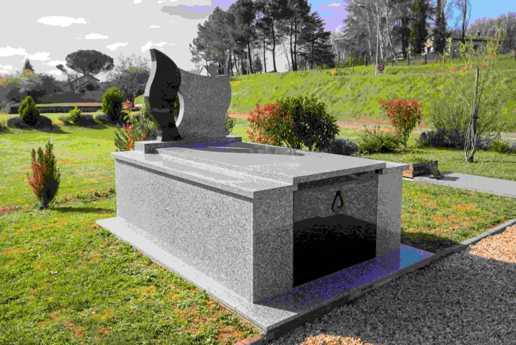 Monument funéraire en granit gris et noir installé dans un jardin paysagé.