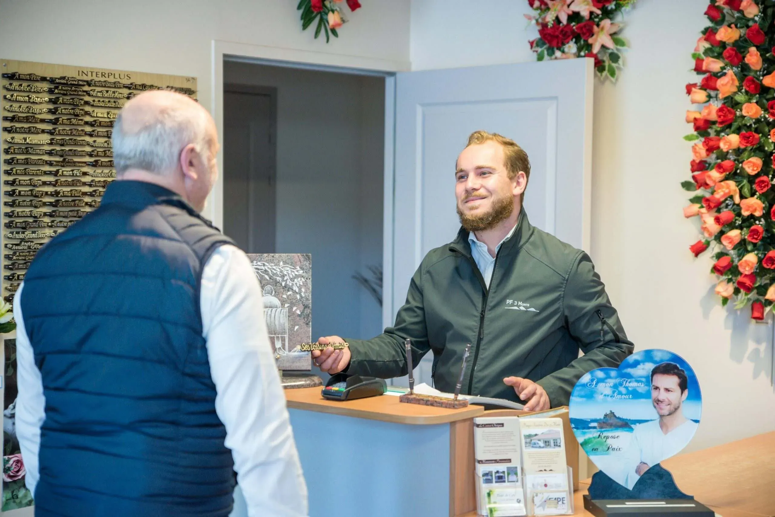 Conseiller funéraire accueillant un client au comptoir de l'agence.