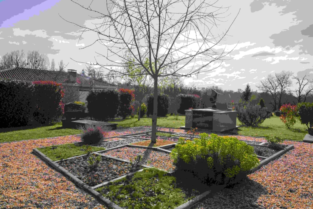Jardin du souvenir aménagé avec arbres, allées gravillonnées et monuments.